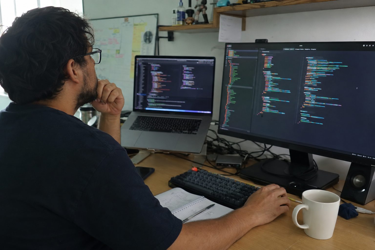 Desarrollador compara código frontend y backend en una laptop y un monitor de escritorio