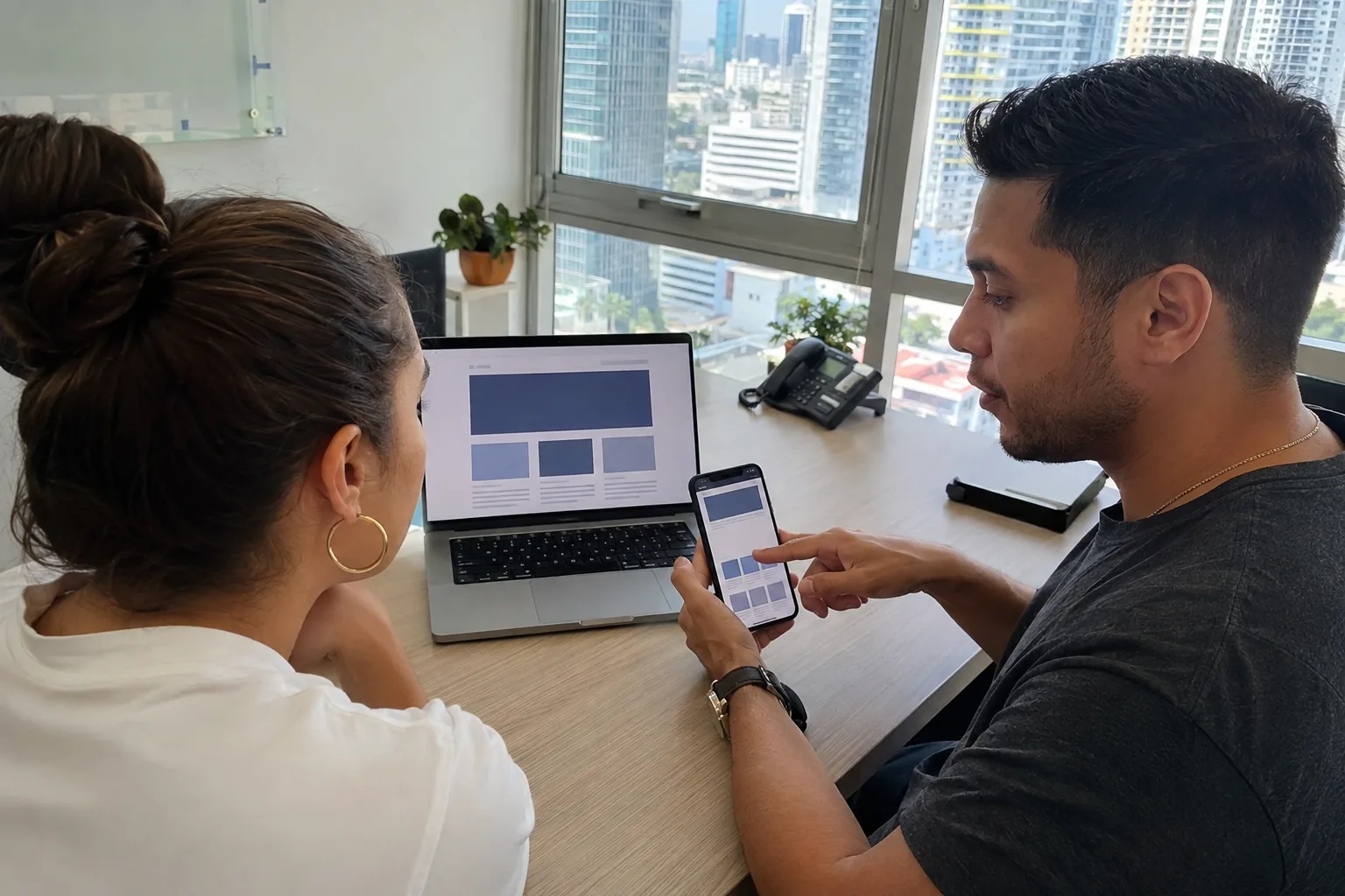 Empresaria y diseñador web comparan una web corporativa y una landing page en una laptop y un celular en Panamá